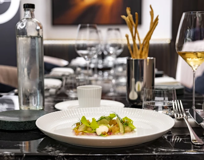 OTTO für dich Ein elegant gedeckter Tisch, auf dem ein kunstvoll angerichtetes Gericht mit Kräutergarnitur serviert wird, daneben ein Glas Weißwein und stilvolles Besteck.An elegantly set table, serving an artfully plated dish garnished with herbs, accompanied by a glass of white wine and stylish cutlery.