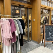 No.Five Eingang Geschäftseingang, davor steht ein Kleiderständer mit flauschigen Oberteilen und ein Schild auf dem steht "Fashion-Alarm Deine neuen Lieblingsstücke sind da!"