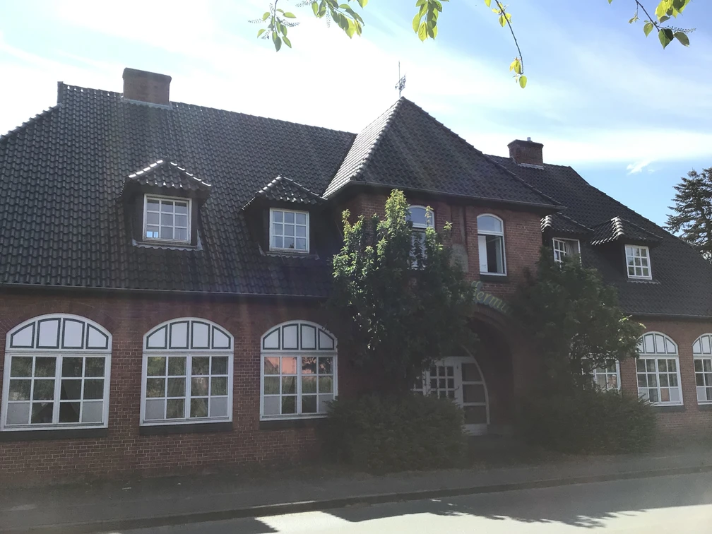Hotel Pfeffermühle Historisches Backsteingebäude mit großen Sprossenfenstern und einem begrünten Eingangsbereich.