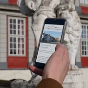 Digitale Stadtführung Smartphone in einer Hand, auf dem Display Informationen über Wolfenbüttel