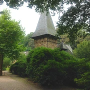 Schloss Caspersbroich von Außen (Privatbesitz) Schloss Caspersbroich in Solingen mit Türmen und üppigem Grün umgeben, steht inmitten dichter Vegetation.