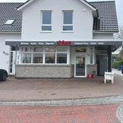Aussenansicht Oba's Das Bild zeigt einen modernen Dönerladen mit einem hellen, weißen Außenanstrich. Über der Eingangstür prangt ein Schild mit der Aufschrift "Obas's".