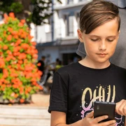 Stadtrallye mit Familie Eine Familie erkundet gemeinsam eine Stadtrallye. Zwei Kinder fokussieren sich auf ein Smartphone.