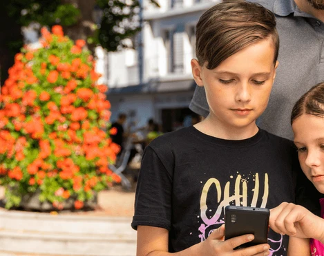 Stadtrallye mit Familie Eine Familie erkundet gemeinsam eine Stadtrallye. Zwei Kinder fokussieren sich auf ein Smartphone.