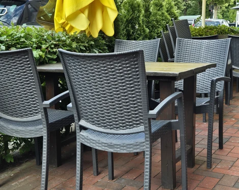 Terasse Restaurant Kibar Ein gemütlicher Außenbereich mit geflochtenen Stühlen unter strahlend gelben Sonnenschirmen.