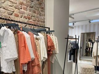 Simon und Renoldi  Im Bild sind modische, sommerliche Kleidung auf Kleiderständern in einem schicken Geschäft mit Ziegelwänden zu sehen.The picture shows fashionable, summery clothes on clothes racks in a chic store with brick walls.