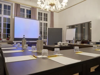 Tagungsraum Tauts im Sonnenresort Ettershaus - Bad Harzburg Tagungsraum Tauts im Sonnenresort Ettershaus mit gedecktem Tisch, Präsentationstechnik und eleganten Kronleuchtern.