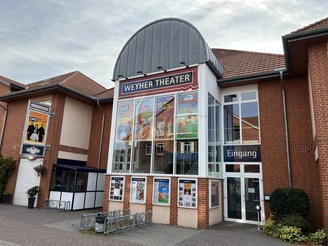 Weyher Theater Backsteingebäude mit Aufschrift "Weyher Theater", Plakate kultureller Veranstaltungen am Eingang.