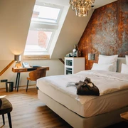 Gästezimmer in der Marienburg Monheim  Modern eingerichtetes Gästezimmer mit einem großen Bett, Schreibtisch und warmem Lichteinfall.