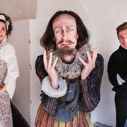 Lerche 1 groß.jpg Drei Schauspieler in historischer Kleidung lächeln lebhaft in einem hellen, beigen Raum.