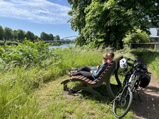 Radfahrer in der Mittelweser-Region Ein Paar entspannt auf einer Bank am Flussufer der Mittelweser, Fahrräder lehnen im Vordergrund.