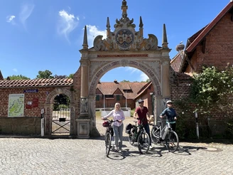 Weserrenaissance-Torbogen Drakenburg Drei Personen stehen mit Fahrrädern vor einem verzierten Torbogen aus der Weserrenaissance.