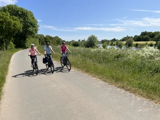 Radfahrer in der Mittelweser-Region Drei Radfahrer fahren bei sonnigem Wetter auf einem asphaltierten Weg durch die grüne Mittelweser-Region.