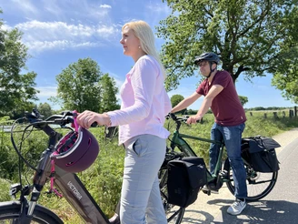 Radfahren in der Mittelweser-Region Zwei Personen mit Fahrrädern auf einem sonnigen, von Bäumen gesäumten Radweg in der Mittelweser-Region.
