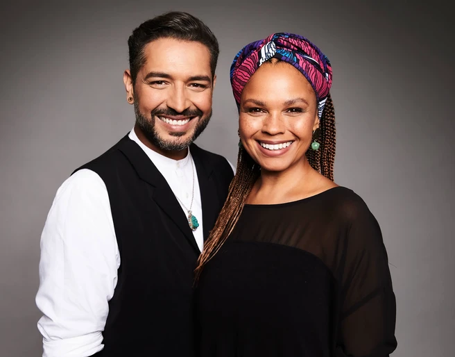 Gianni Jovanovic Oyindamola Alashe Gianni Jovanovic und Oyindamola Alashe lächeln herzlich in die Kamera vor neutralem Hintergrund.Gianni Jovanovic and Oyindamola Alashe smile warmly into the camera against a neutral background.