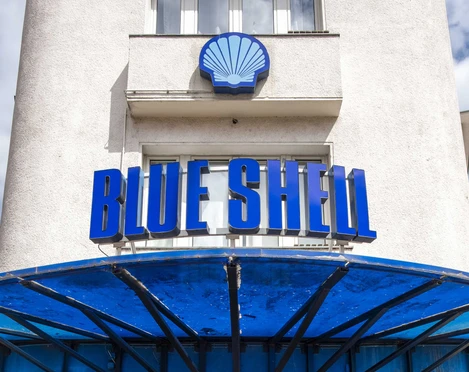 Blue Shell Das Bild zeigt den Eingangsbereich des Veranstaltungsortes „Blue Shell“ in Köln. Über dem Eingang prangt ein auffälliges, blaues Schild mit dem Schriftzug „Blue Shell“. Das Gebäude hat eine helle Fassade, wobei der Eingangsbereich in Blau gehalten ist. Ein Vordach aus Metall bietet Schutz vor Witterungseinflüssen und unterstreicht das zeitgemäße Design des Clubs.The image shows the entrance area of the venue "Blue Shell" in Cologne. Above the entryway is a prominent blue sign featuring the inscription "Blue Shell." The building has a light-colored facade, while the entry area is accented in blue. A metal canopy provides weather protection and emphasizes the contemporary design of the club.