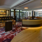 Innenraum im Restaurant merk.Mahl  Moderner Innenraum eines Restaurants mit eleganter Bar, Holzboden und stilvollem Teppichmuster.