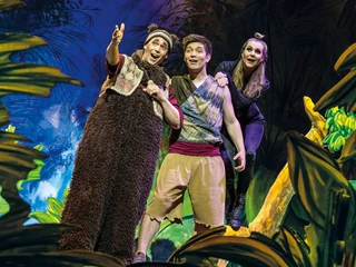 Dschungelbuch - das Musical 2 (c) Theater Liberi.jpg Drei Darstellende in Kostümen auf einer bunten Bühnenlandschaft. Einer zeigt mit erhobenem Arm auf etwas in der Ferne und die beiden anderen staunen.