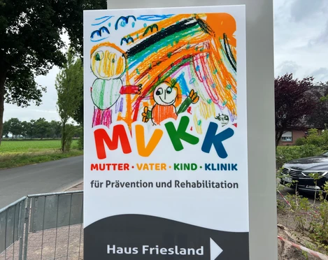 MVKK.Logo.jpg Das Schild zeigt ein buntes Logo der "Mutter-Vater-Kind-Klinik" mit Kindern in fröhlichen Farben.