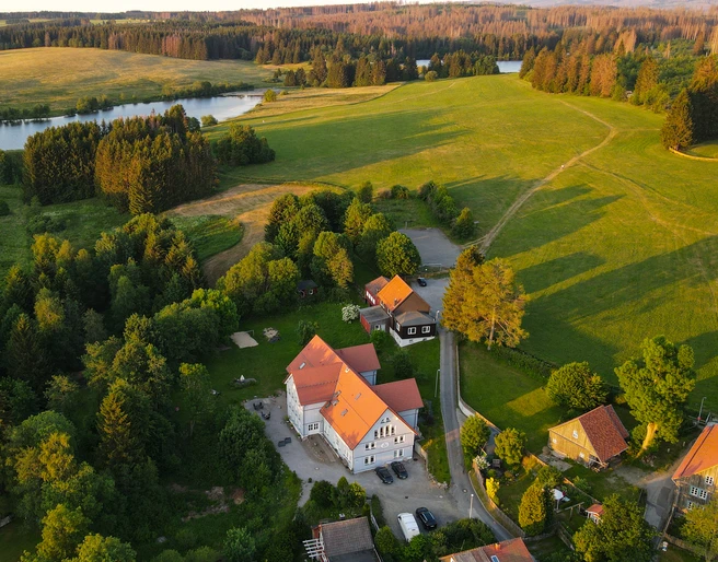 Harz-Urlaubs-Alm in Buntenbock - Hotel, Wiesen und Teich aus der Luft Die Luftaufnahme zeigt das idyllisch gelegene Hotel Urlaubs-Alm Buntenbock im Harz, umgeben von saftigem Grün und einem Teich. Ein perfekter Rückzugsort inmitten der Natur.