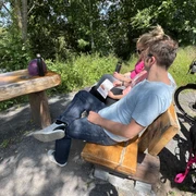 Radfahren in der Mittelweser-Region Ein Paar sitzt auf einer Holzbank in einem schattigen Park, neben ihnen stehen Fahrräder.