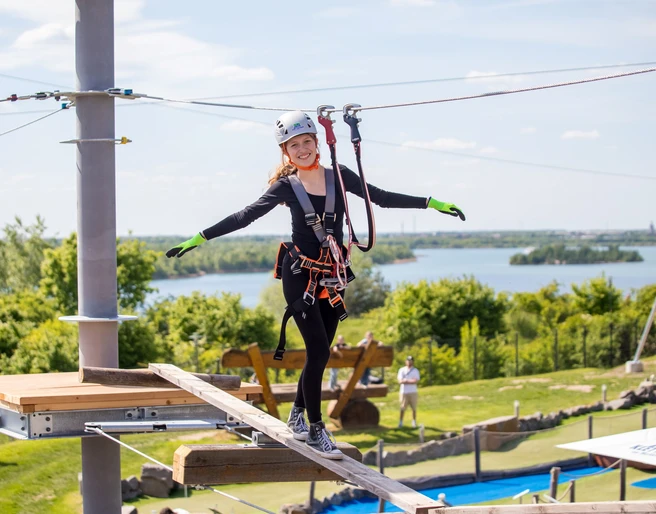 Kletterpark Markkleeberg - Freizeitaktivitäten in Leipzig und Region.jpg Eine junge Frau balanciert über einen Holzbalken im Kletterpark Markkleeberg, im Hintergrund ist der Markkleeberger See zu erkennen.