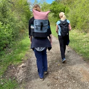 Wandern in der Mittelweser-Region Zwei Wanderer mit Rucksäcken gehen einen naturbelassenen Weg in der grünen Mittelweser-Region entlang.