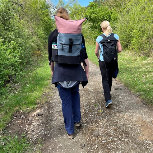 Wandern in der Mittelweser-Region Zwei Wanderer mit Rucksäcken gehen einen naturbelassenen Weg in der grünen Mittelweser-Region entlang.