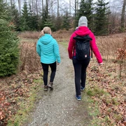 Wandern in der Mittelweser-Region Zwei Menschen in farbigen Jacken und Rucksäcken wandern in einem Waldgebiet auf einem schmalen Pfad.