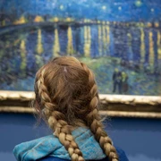 11 Sekunden_Van Gogh (c) Stefan Draschan.jpg Ein Mädchen mit blonden Haaren und einem geflochtenen Zopf steht vor einem blauen Van Gogh Gemälde mir Sternenhimmel.