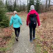 Wandern in der Mittelweser-Region Zwei Personen spazieren auf einem schmalen Waldweg, umgeben von kahlen Bäumen mit leichtem Laub.