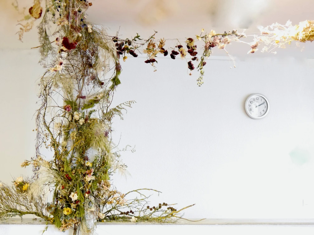 In einem Raum mit weißen Wänden, an denen eine Uhr hängt, ist eine große Blumenranke installiert.