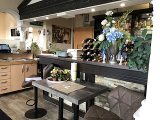 Restaurant Olympia  Einladendes Restaurant mit dekorierten Tischen, eleganter Theke und schönem Blumenschmuck im Vordergrund.