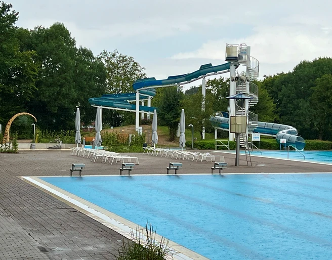 Freizeitbad Münchehagen Freizeitbad Münchehagen: Großer Außenbereich mit Wasserrutsche, umgeben von Bäumen und Liegestühlen.