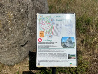 Findling Brokeloh Ein Findling im Gras mit einer informativen Tafel, die Details zur Geschichte und zur Lage bietet.