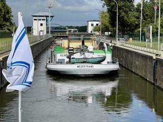 Schleuse Langwedel Ein Frachtschiff namens Wesertrans passiert die Schleuse Langwedel, umgeben von grüner Natur.