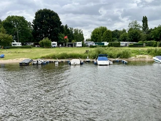 Campingplatz Horstedt Campingplatz Horstedt mit Wohnwagen und Zelten am Flussufer, umgeben von saftigem Grün.