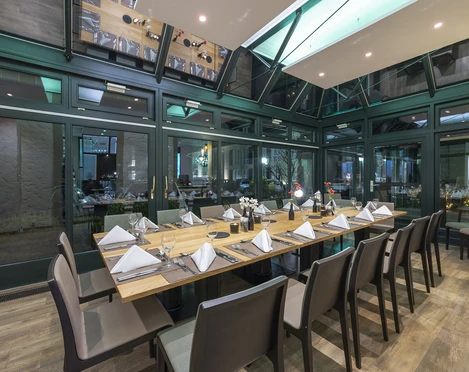 Wintergarten im Restaurant Blattwerk im Fletcher Hotel-Restaurant Waldhotel Nordrhein-Westfalen Restaurant Wintergarten mit elegant gedecktem Esstisch unter einem modernen Glasdach in Heiligenhaus.