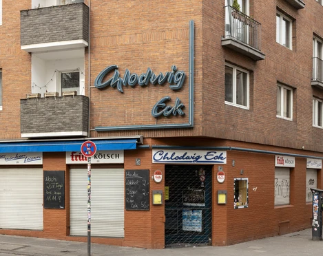 Chlodwig Eck Das Bild zeigt die Backsteinfassade der Eckkneipe "Chlodwig Eck" in Köln mit blauer Neonaufschrift.The picture shows the brick façade of the corner pub "Chlodwig Eck" in Cologne with blue neon lettering.