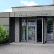 Moderner Eingang einer Volkshochschule mit barrierefreien Zugangsrampen und automatischen Türen.