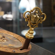 Blick in die Ausstellung Uhrenschloss Ein kunstvoller Schlüssel mit goldenen Verzierungen und detaillierten Ornamenten in einer Vitrine.