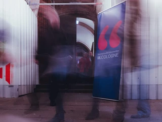 lit.COLOGNE Menschen gehen an einem Banner mit der Aufschrift „lit.COLOGNE“ vorbei.People walk past a banner with the inscription "lit.COLOGNE".