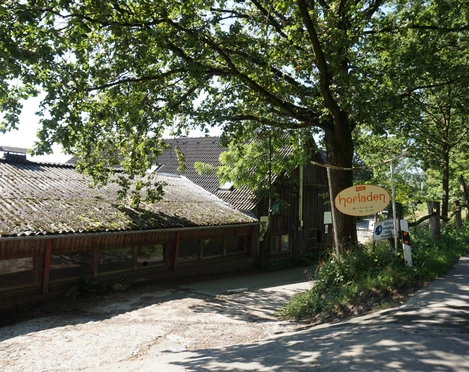 Örkhof mit Hofladen Velbert Eingang zum Örkhof mit Hofladen in Velbert, umgeben von grünen Bäumen und ländlichen Gebäuden.