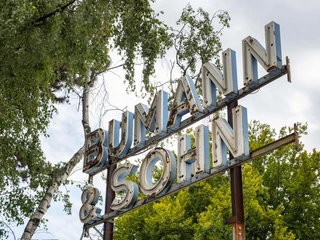 Bumann & Sohn Ein Metall-Schild mit der Aufschrift "Bumann & Sohn" erhebt sich gegen den bewölkten Himmel.A metal sign with the inscription "Bumann & Sohn" rises up against the cloudy sky.