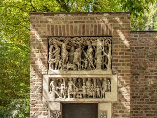 St. Alban Eine Sandsteinfassade mit aufwendig gestalteten Reliefs umrahmt liebevoll eine Holztür.A sandstone façade with elaborately designed reliefs lovingly frames a wooden door.