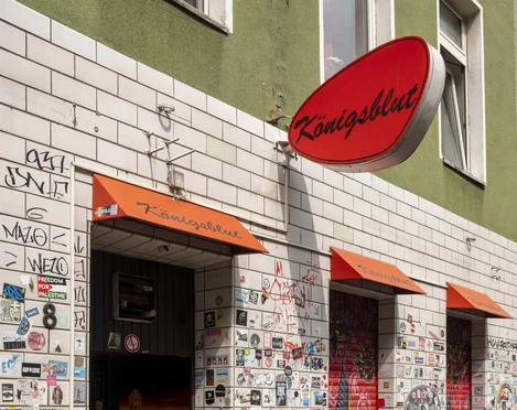 Königsblut Eine mit bunten Aufklebern bedeckte Wand am Eingang einer Bar namens "Königsblut" in Köln.A wall covered in colorful stickers at the entrance to a bar called "Königsblut" in Cologne.