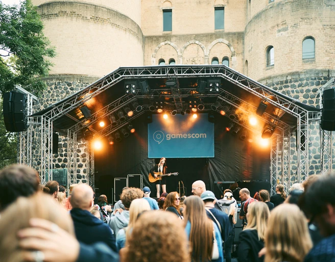 gamescom city festival Ein Gitarrenspieler performt auf einer outdoor-Bühne, umgeben von einem Publikum vor einer historischen Festung.A guitar player performs on an outdoor stage, surrounded by an audience in front of a historic fortress.