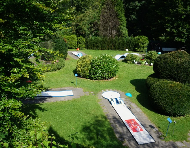 Minigolf Binder_01_Stadt Velbert_Lisa Krick.JPG Eine Minigolfanlage eingebettet in grüne Hecken und Rasenflächen, mit mehreren Bahnen und schattigen Ecken.