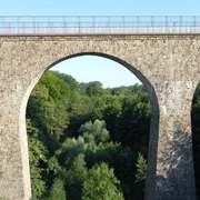 Saubrücke Velbert 01_Stadtmarketing Velbert.JPG Eine imposante Steinbrücke mit drei Bögen überspannt einen üppig bewachsenen Wald in Velbert.