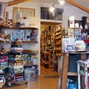 Spielbrett (interior) Innenraum eines gut sortierten Brettspielladens mit einer Fülle an bunten Spieleschachteln, die auf Regalen und Böden gestapelt sind. Eine helle Deckenbeleuchtung sorgt für eine einladende Atmosphäre.Interior of a well-stocked board game store with an abundance of colorful game boxes stacked on shelves and floors. Bright ceiling lighting creates an inviting atmosphere.